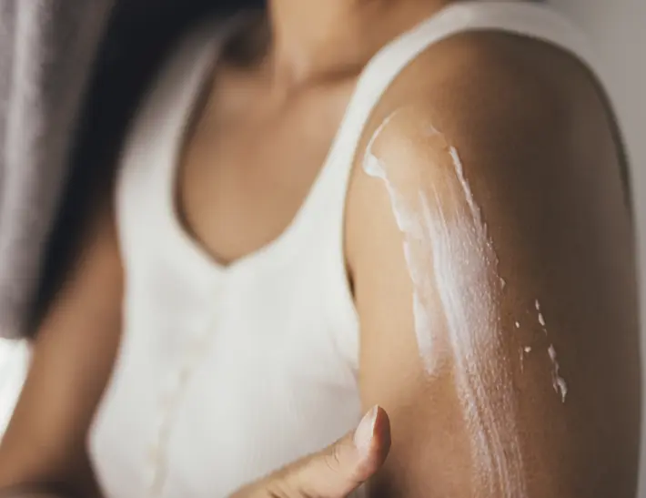 Woman apply lotion to shoulder area